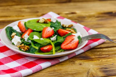 Tahta masada çilekli, ıspanaklı, cevizli ve peynirli taze sağlıklı salata.