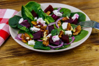 Haşlanmış pancar, peynir, ceviz ve ahşap masada kırmızı soğanlı ıspanak salatası. Sağlıklı vejetaryen yemekleri