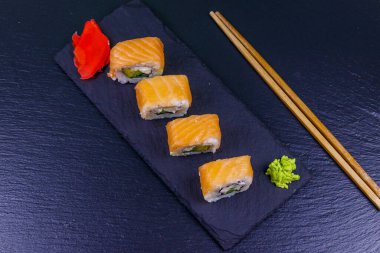 Suşi Philadelphia 'yı siyah bir levhada yuvarlıyor. Üst görünüm