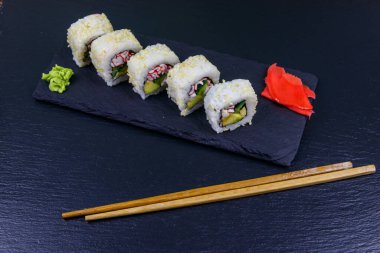 Uramaki suşisi siyah tahtada surimi ile yuvarlanır.