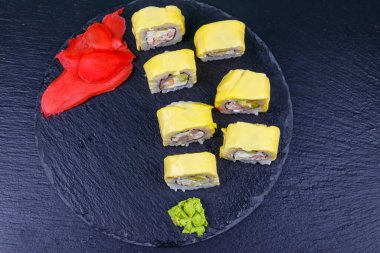 Suşi peyniri siyah tahtada yuvarlanıyor. Üst görünüm