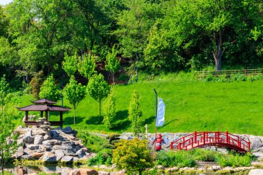 Japon bahçesindeki bir göletin yanında kırmızı köprü ve çardak.