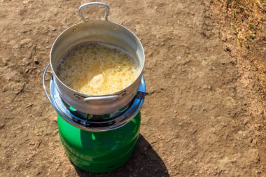 Propan gazı silindirinde küçük alüminyum tava ve açık havada pişirmek için yakıcı. Açık havada, kampta yemek pişirmek için gerekli ekipman. Seyahat kavramı