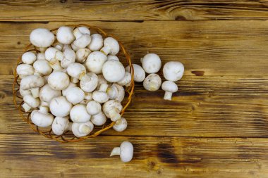 Tahta masada hasır sepetin içinde taze şampiyon mantarları. Üst görünüm