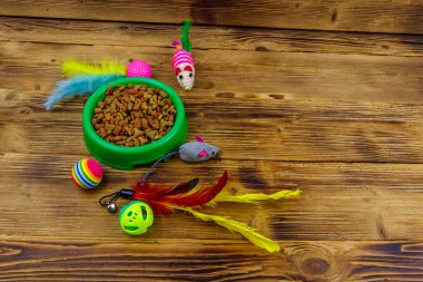 Kedi ve kase için tahta arka planda ev hayvanı yiyeceği olan oyuncaklar. Hayvan bakımı konsepti