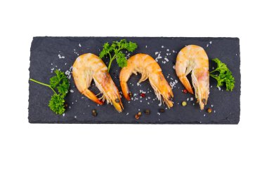 Beyaz arka planda izole edilmiş tahta üzerinde maydanozlu, tuzlu ve biberli büyük çiğ karidesler. Üst görünüm