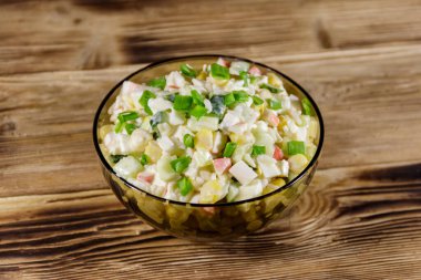 Yengeç çubuklu salata, mısır, salatalık, yumurta, pirinç ve mayonez ahşap masada.