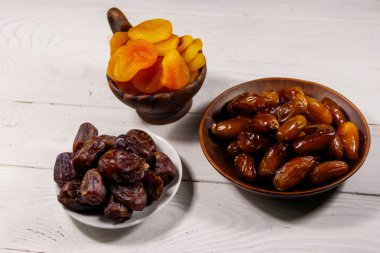 Kurumuş kayısılar ve beyaz ahşap masada meyveler.