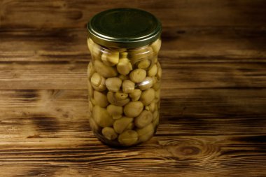 Ahşap masada cam kavanozda marine edilmiş lezzetli mantarlar.