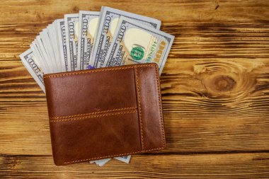 Kahverengi deri cüzdan ve ahşap masada Amerikan doları. Üst görünüm