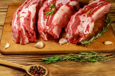 Baharatlı çiğ domuz kaburgası, sarımsak ve ahşap masada biberiye.