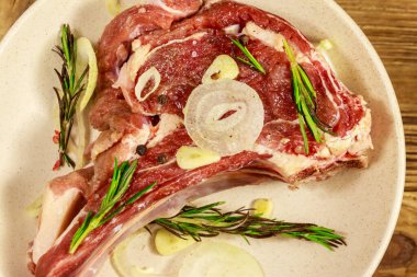 Kemik üzerinde marine edilmiş biftek, baharat, soğan ve ahşap masada biberiye.