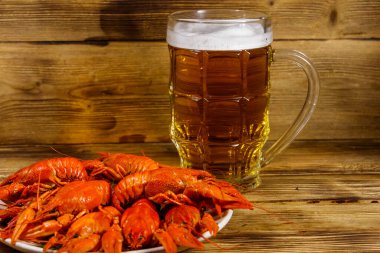 Haşlanmış kerevit ve bir kupa bira ahşap masada.