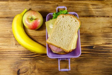 Sandviç, muz ve elmayla dolu bir beslenme çantası. Üst görünüm