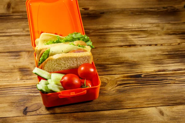 饭盒上有三明治和新鲜蔬菜 放在木制桌子上 — 图库照片
