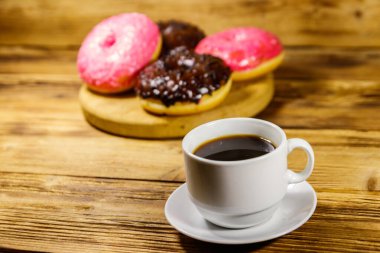 Bir fincan kahve ve lezzetli çörekler ahşap bir masada.