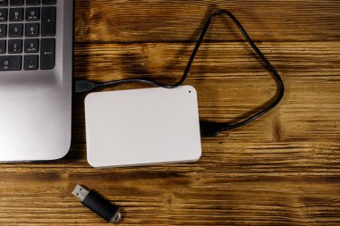 Harici HDD, tahta bir masadaki dizüstü bilgisayara ve USB flash diske bağlı. Üst Manzara. Veri depolama kavramı