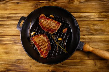 Biberiyeli ızgara domuz bifteği, sarımsak ve ahşap masada ızgara demir tavada baharat. Üst görünüm