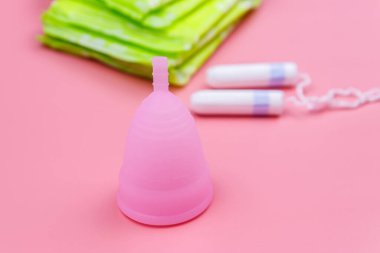 Pembe arka planda hijyenik ped, tampon ve regl kupası. Kritik günler, regl dönemi, kadın hijyeni