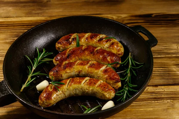 Bratwürste Mit Rosmarin Knoblauch Und Gewürzen Gusseiserner Grillpfanne Auf Holztisch — Stockfoto