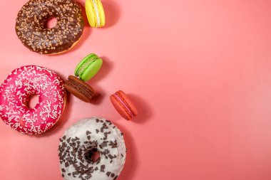 Pembe arka planda lezzetli çörekler ve kurabiyeler. Üst görünüm, alanı kopyala