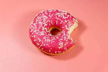 Pembe arka planda lezzetli, pembe bir çörek. Üst görünüm