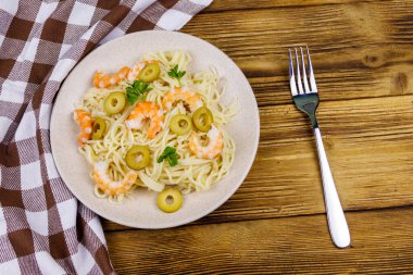 Karidesli spagetti makarna, yeşil zeytin ve ahşap masada maydanoz. Üst görünüm