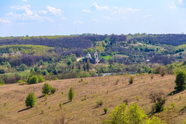 Orta Ukrayna 'da orman, çayır, tepeler, göl, küçük köy ve ortodoks kilisesi olan bahar manzarası
