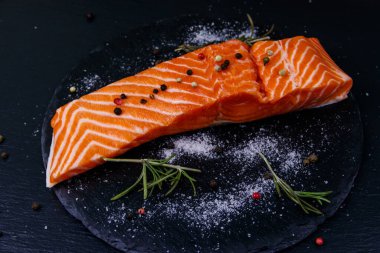 Çiğ somon fileto ve siyah tahtada baharat.