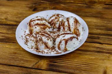 Tahta bir masada beyaz tabakta çikolatalı vanilyalı dondurma.