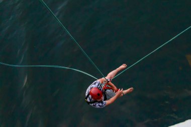 Köprünün yüksek irtifasından ip atlama. Güzel nehrin üzerindeki yaya köprüsünden bungee jumping.