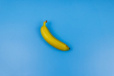 Pastel mavi arka planda sarı muz. Üst görünüm, düz görünüm, minimal dizayn