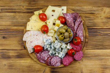 Zeytinli antipasti tabağı, kiraz domatesleri, ahşap bir masada İtalyan salamı ve peyniri çeşitleri. Üst görünüm