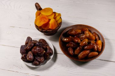 Kurumuş kayısılar ve beyaz ahşap masada meyveler.