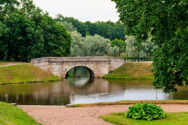 Rusya 'nın Gatchina kentindeki bir gölde taş kemer köprüsü.