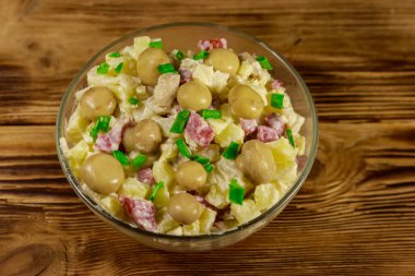 Ahşap masada marine mantar, sosis, soğan ve mayonez ile patates salatası