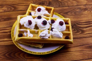 Dondurmalı Belçika waffle 'ı ve ahşap masada böğürtlen.