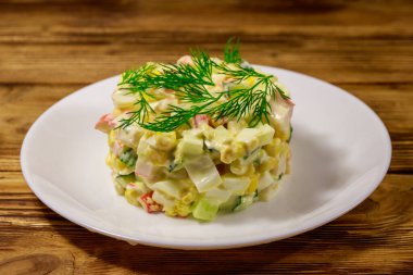 Yengeç çubuklu salata, tatlı mısır, salatalık, yumurta ve mayonez ahşap masada.