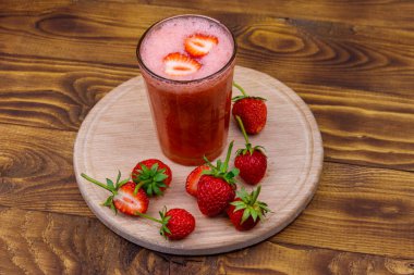 Tahta masada bir bardak taze çilekli smoothie.