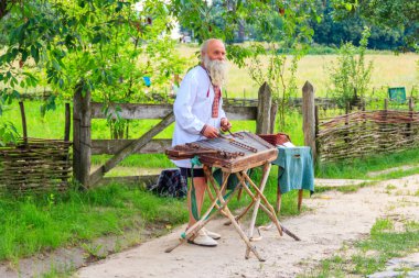 Kiev, Ukrayna - 28 Haziran 2020: Ukrayna 'nın Kiev kenti yakınlarındaki Pyrohiv (Pirogovo) köyünde Gusli oynayan yaşlı Ukraynalı adam