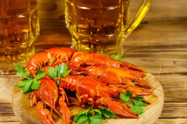 Haşlanmış kerevit ve tahta bir masada iki kupa bira.