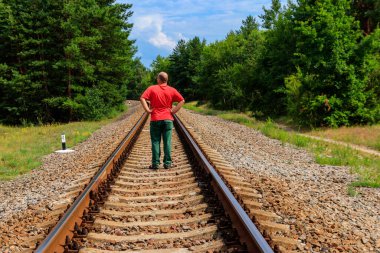 Yalnız adam tren yolunda yürüyor.
