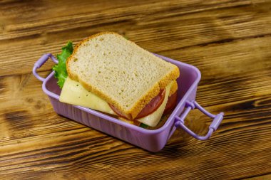 Tahta bir masanın üzerinde sandviç olan beslenme çantası.