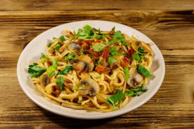 Mantarlı makarna ve ahşap masada domates sosu.