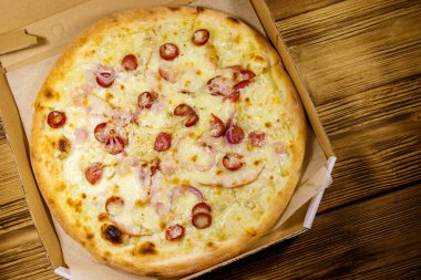Tahta bir masanın üzerindeki karton kutuda nefis taze pizza. Üst Manzara. Yemek teslimatı, fast food, pizza teslimatı.