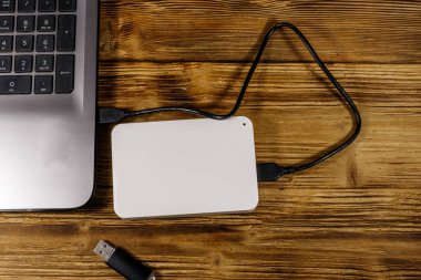 Harici HDD, tahta bir masadaki dizüstü bilgisayara ve USB flash diske bağlı. Üst Manzara. Veri depolama kavramı
