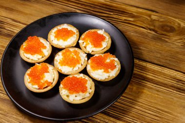 Kırmızı havyarlı turta ve ahşap bir masada yumuşak peynir.