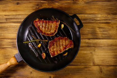 Biberiyeli ızgara domuz bifteği, sarımsak ve ahşap masada ızgara demir tavada baharat. Üst görünüm