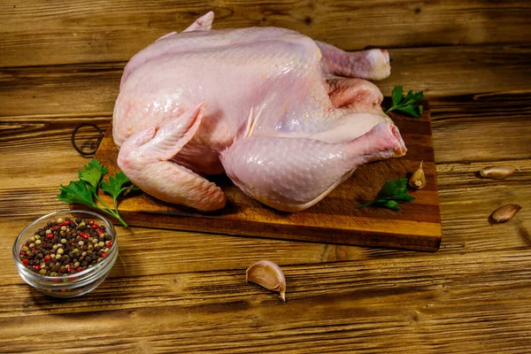 Raw whole chicken with spices on a wooden table