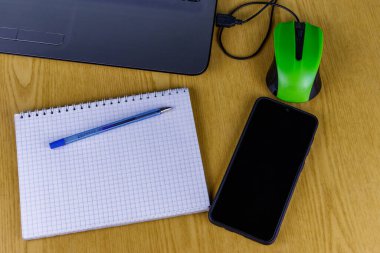 Bilgisayarda fare, akıllı telefon, defter ve kalem var. Üst Manzara. Ev ve iş konseptinde çalışmak